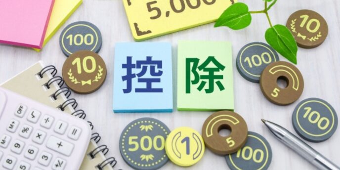 色付きカードに「控除」と書かれ、周囲に電卓、コイン、ペン、付箋、観葉植物が配置されている画像