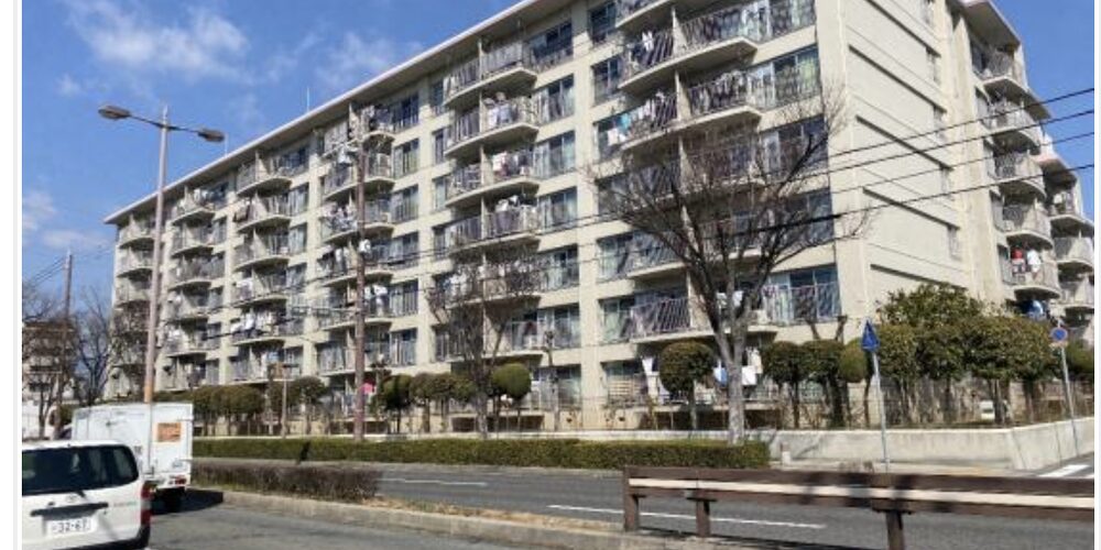 大通りに面した集合住宅の外観。青空の下に建つ中層マンションのイメージ