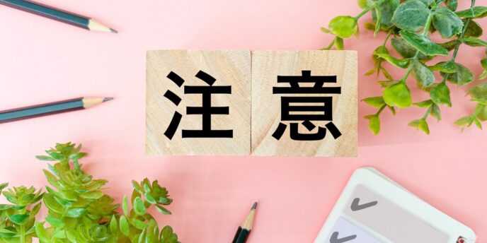 「注意」の文字が書かれた木製ブロックと観葉植物、文具が並ぶ画像