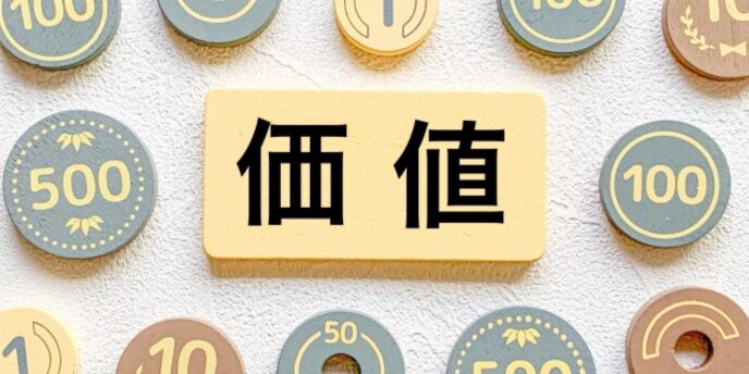 木製チップのコインと「価値」の文字を示したボード、価格や評価を表すイメージ