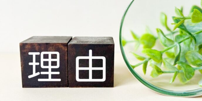「理由」と書かれた木のブロックと観葉植物、物事の根拠や動機を示すイメージ