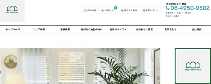 株式会社a&y不動産の公式サイトトップページ。緑のロゴマークと連絡先が表示されており、洗練された白基調のインテリア画像が背景に配置されている