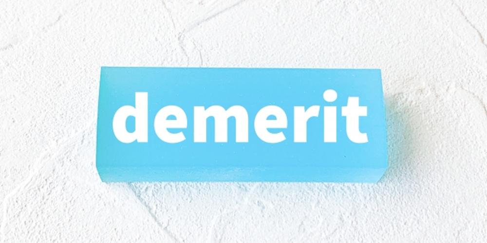 白地に「demerit」と書かれた青いブロック