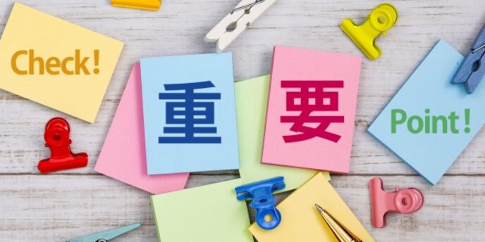 カラフルなメモに「重要」「Check!」「Point!」と書かれ、クリップやペンが並ぶデスク上の画像