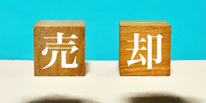 「売却」の漢字が書かれた木のブロック、不動産や資産売却のイメージ