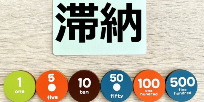 「滞納」と書かれたカードと貨幣チップ、支払い遅延や未納金に関するイメージ