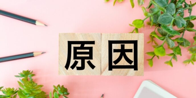 「原因」と書かれた木のブロックと文房具、問題や課題の発生理由を示すイメージ