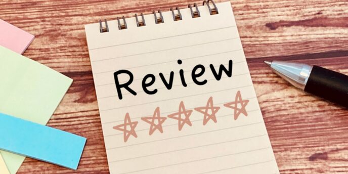 木目のデスク上に置かれたスケッチブックに「Review」と手書きされ、その下に星5つのアウトラインが並ぶレビューイメージ