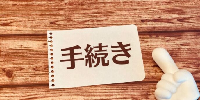 「手続き」と書かれた紙とグッドサイン、手続き完了や承認のイメージ