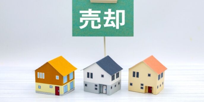 売却案内を象徴する家の模型と「売却」の看板イメージ
