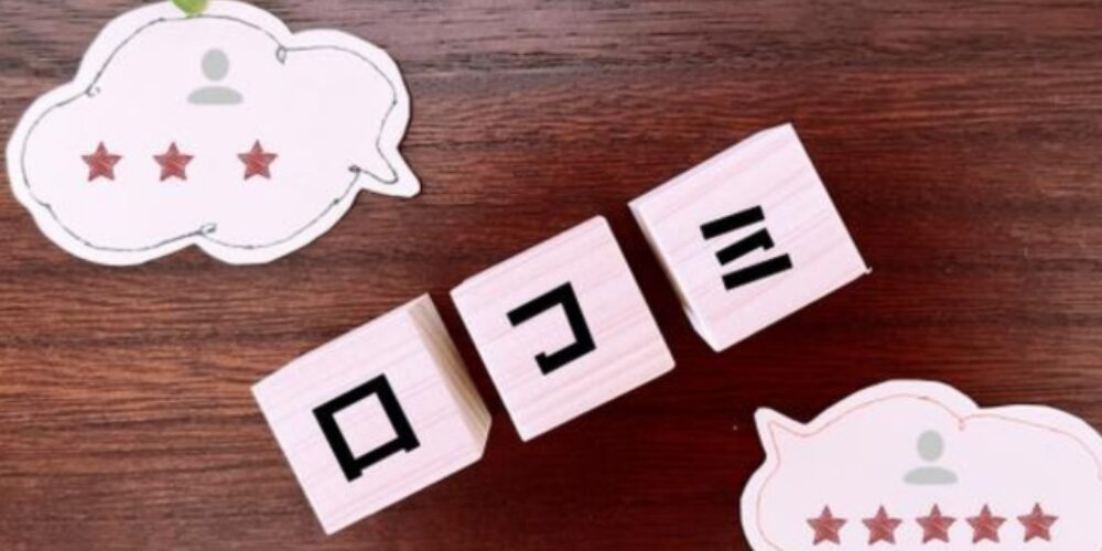 木のテーブル上に置かれた「口コミ」の文字とレビュー評価