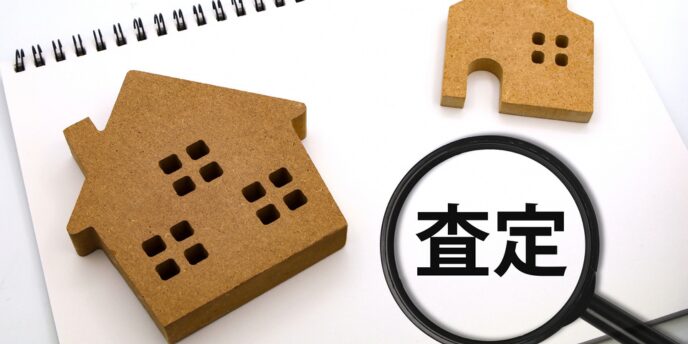 「査定」の文字と家の模型、虫眼鏡が置かれた画像