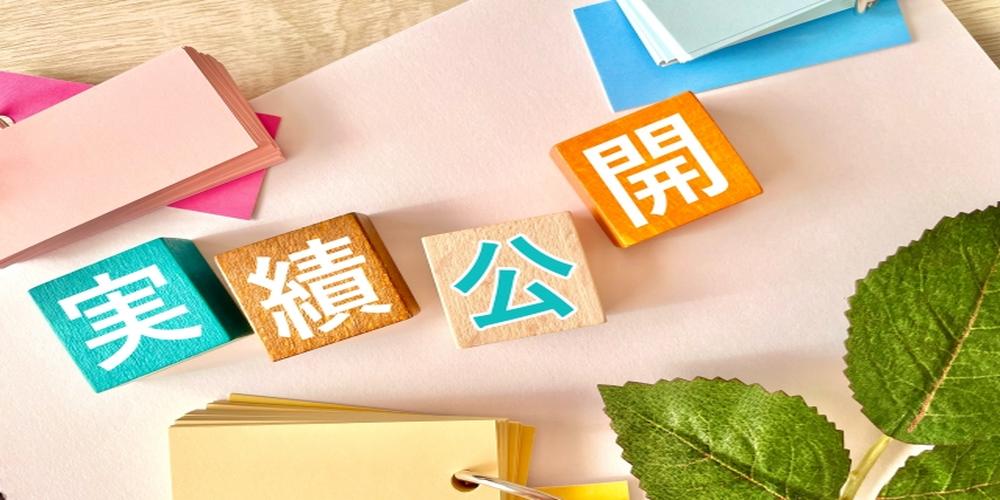 実績公開と書かれたカラフルな積み木と文具が並ぶデスク上の画像
