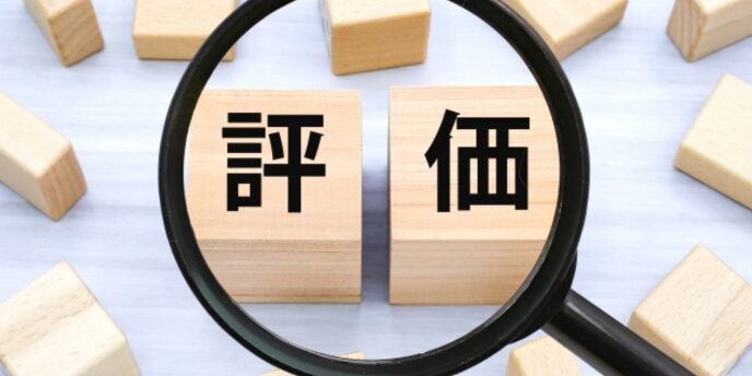 木製ブロックに「評価」と書かれ、拡大鏡で強調された視覚イメージ