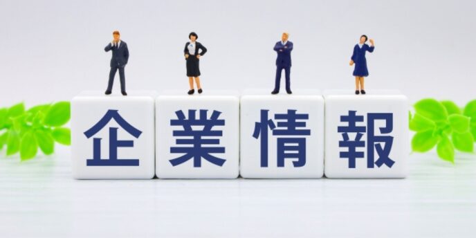 「企業情報」と書かれたキューブの上に、スーツ姿のミニチュア人物4体が立っている画像。