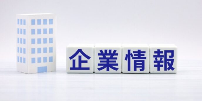 白い背景の上に「企業情報」と書かれたキューブと、左側に青いビルの模型が配置されている画像。