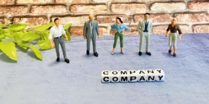 レンガ壁の前にミニチュアの人物5人が立ち、「COMPANY」と書かれたキューブが手前に並ぶ画像。