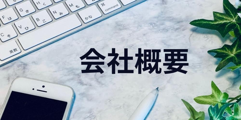 キーボードとスマートフォン、観葉植物が並ぶデスク上に『会社概要』の文字