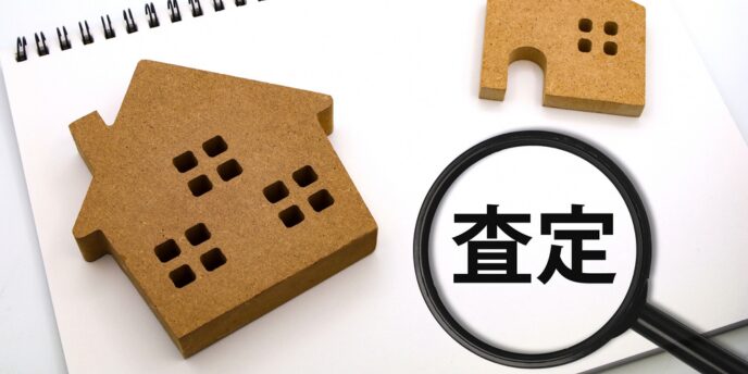 「査定」の文字と家の模型、虫眼鏡が置かれた画像