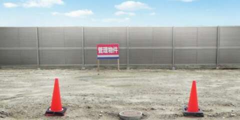 更地に立つ「管理物件」の看板と赤いパイロン