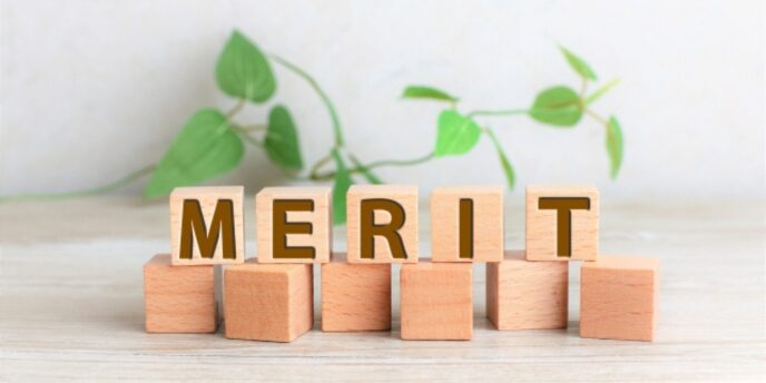 木の背景に置かれた「MERIT」ブロックと植物の演出