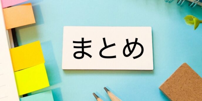 青い背景に「まとめ」と書かれたカードが中央にあり、周囲に文房具やふせんが並べられている画像