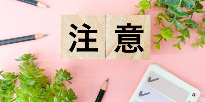 「注意」と書かれた木製ブロックと観葉植物、チェックリストが並ぶ画像