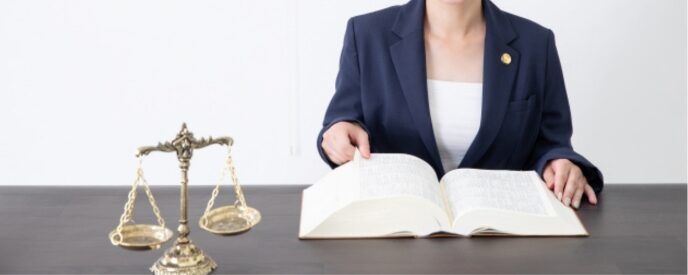 法律書を読む弁護士と天秤、法的手続きや相談のイメージ