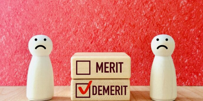 赤い背景に悲しげな表情の木製フィギュア2体と、「DEMERIT」にチェックマークが付いた積み木が並ぶデメリット強調イメージ