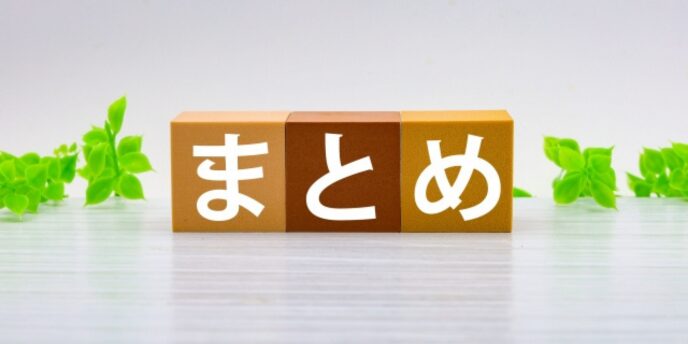 木のブロックにまとめと書かれ、背景に緑の植物