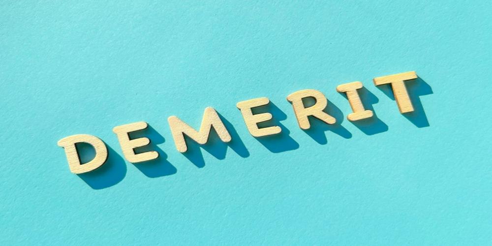 DEMERITの文字が水色の背景に並ぶ木製アルファベットの構成