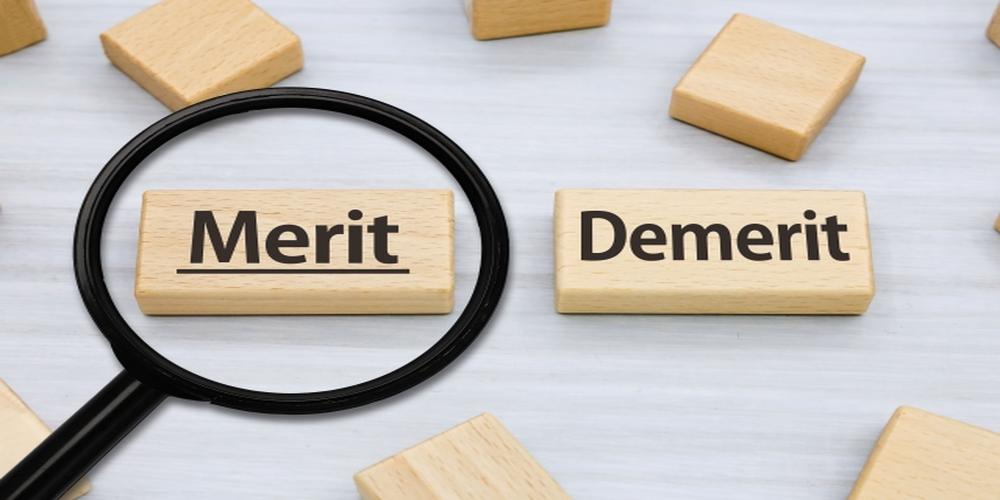 MeritとDemeritの木製ブロックに虫眼鏡がかけられた比較イメージ