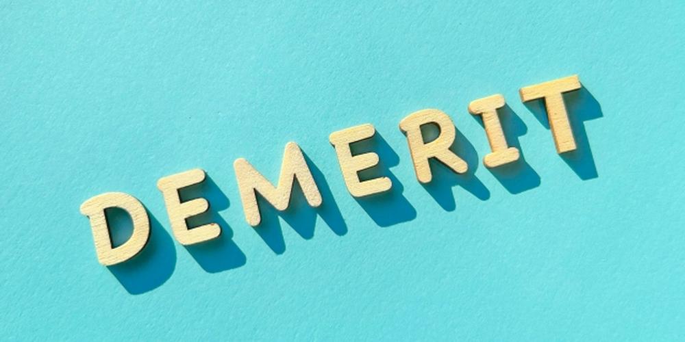 『DEMERIT』の文字が木製で並べられた、水色背景のイメージ