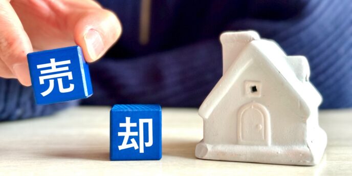 「売却」と書かれた青いブロックと白い家の模型が並ぶ画像