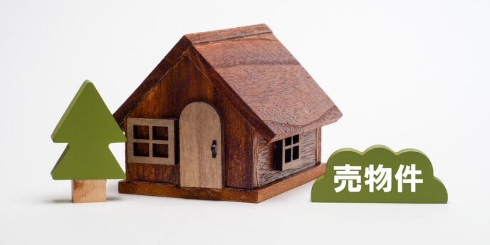 木製の家の模型と「売物件」の札が並ぶ画像