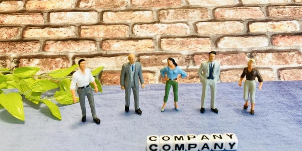 「COMPANY」の文字ブロックと並ぶ、さまざまな服装のビジネスパーソンのフィギュア